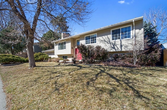 raised ranch featuring a chimney and a front yard