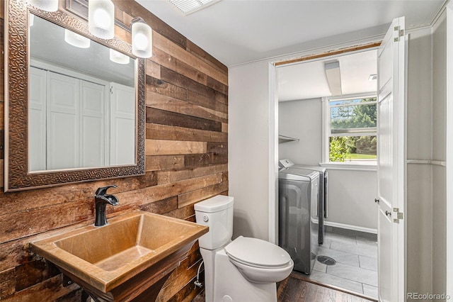 8727 E Girard Ave, Denver, CO 80231 - bathroom with washing machine and dryer, wood walls, and wood finished floors