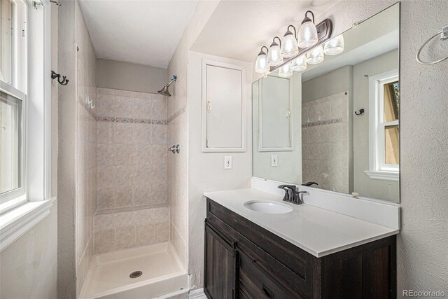 8727 E Girard Ave, Denver, CO 80231 - full bathroom with vanity, tiled shower, and a textured wall