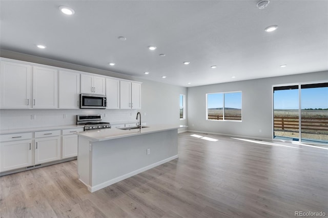 13398 E 99th Pl, Commerce City, CO 80022 - kitchen featuring appliances with stainless steel finishes, a sink, open floor plan, a kitchen island with sink, and tasteful backsplash