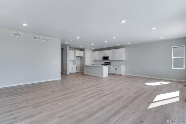 13398 E 99th Pl, Commerce City, CO 80022 - unfurnished living room with baseboards, recessed lighting, light wood-type flooring, and a sink