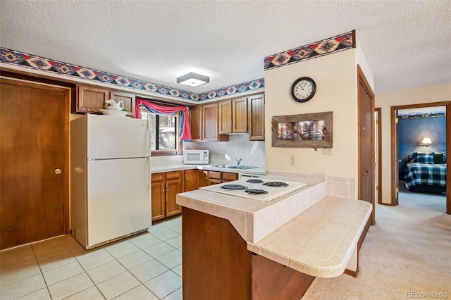 kitchen with sink, white appliances, light tile patterned floors, a kitchen breakfast bar, and kitchen peninsula