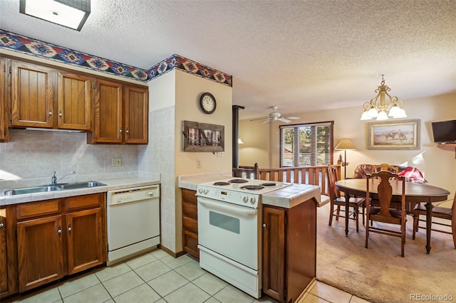 kitchen with sink, decorative light fixtures, kitchen peninsula, white appliances, and backsplash