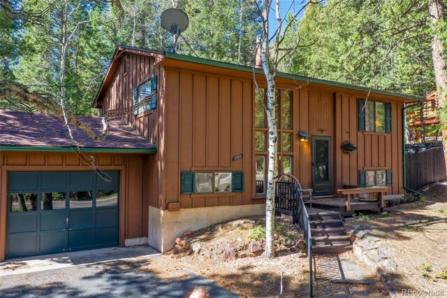 1321 W Midland Ave, Woodland Park, CO 80863 - chalet / cabin featuring a garage, board and batten siding, and asphalt driveway