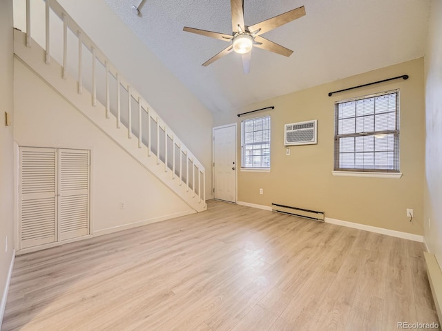 unfurnished living room featuring ceiling fan, a wall mounted air conditioner, light hardwood / wood-style flooring, a baseboard heating unit, and a textured ceiling