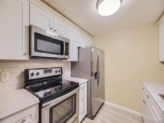 kitchen with backsplash, white cabinetry, and stainless steel appliances