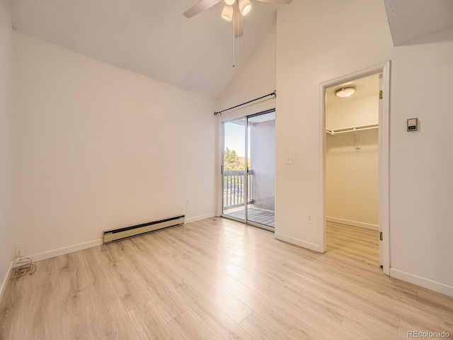 unfurnished bedroom featuring access to outside, baseboard heating, a spacious closet, light hardwood / wood-style floors, and a closet