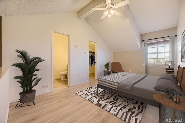 bedroom with ceiling fan, light hardwood / wood-style flooring, lofted ceiling with beams, a walk in closet, and a closet