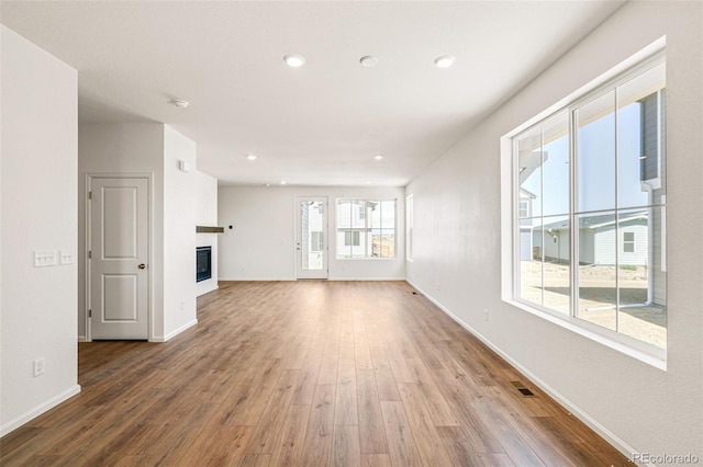 9343 Biscay St, Commerce City, CO 80022 - unfurnished living room with recessed lighting, baseboards, a glass covered fireplace, visible vents, and wood finished floors