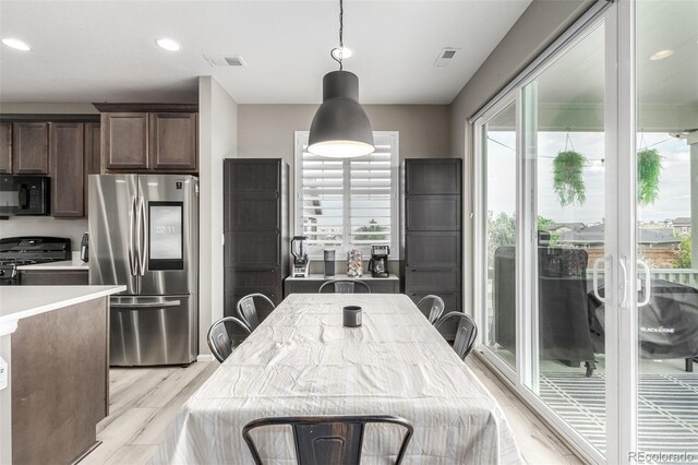 interior space with black appliances, light hardwood / wood-style flooring, pendant lighting, and dark brown cabinetry