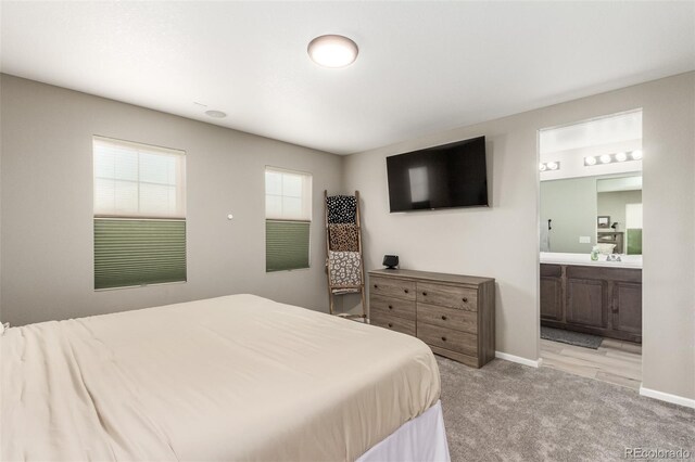 bedroom featuring ensuite bath, sink, and light carpet