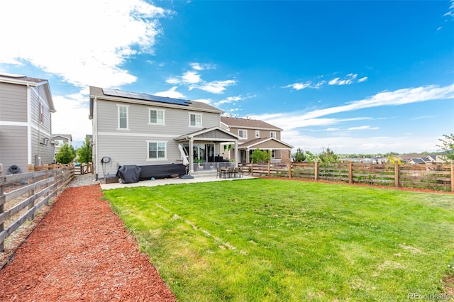 rear view of house with an outdoor living space, a patio area, a lawn, solar panels, and a gazebo