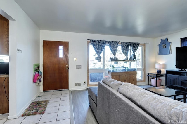 living area featuring light tile patterned floors, baseboards, and visible vents