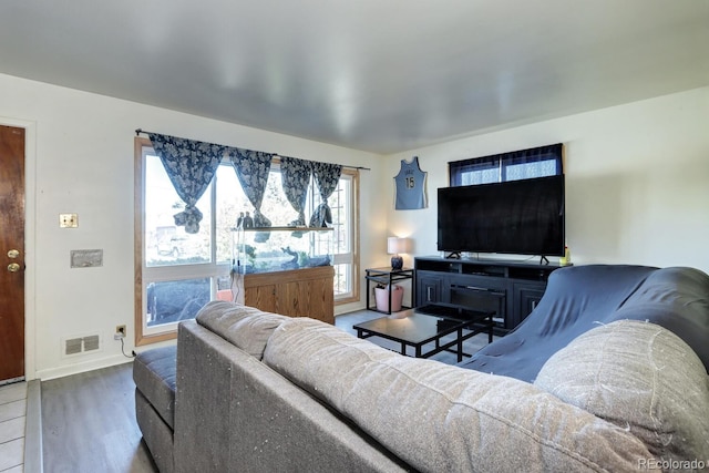 living area with baseboards, visible vents, and wood finished floors