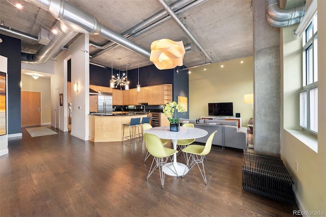 dining space featuring a high ceiling, baseboards, and dark wood finished floors