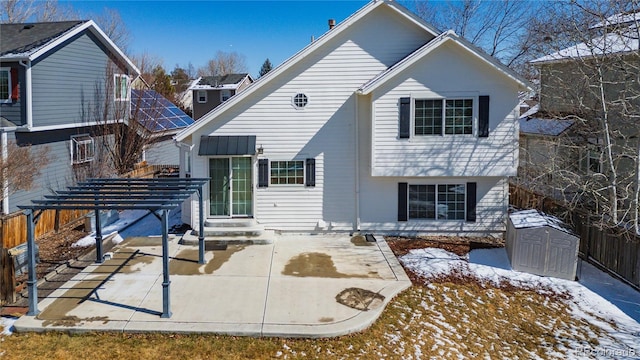 snow covered house featuring an outbuilding, a fenced backyard, a shed, and a patio area