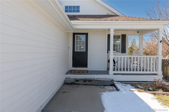 view of exterior entry featuring a porch and a shingled roof