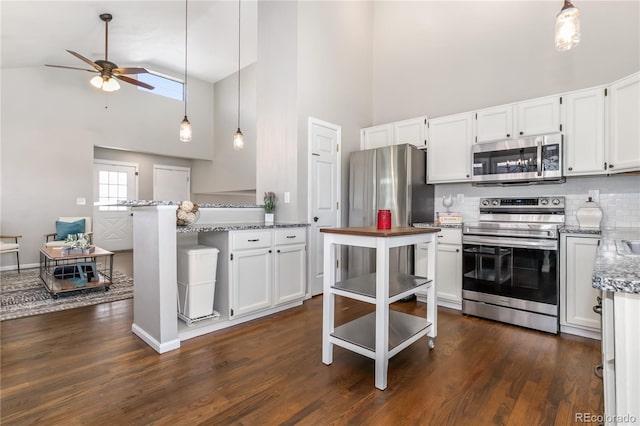 kitchen featuring light stone counters, white cabinets, appliances with stainless steel finishes, and dark wood-type flooring