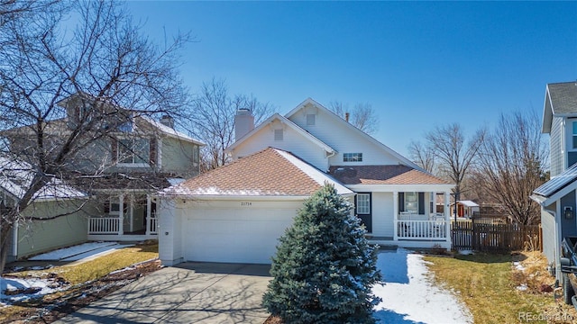 traditional home featuring fence, a porch, a chimney, concrete driveway, and a garage