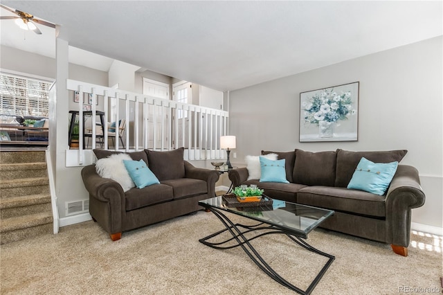 living area with visible vents, baseboards, carpet, stairway, and a ceiling fan