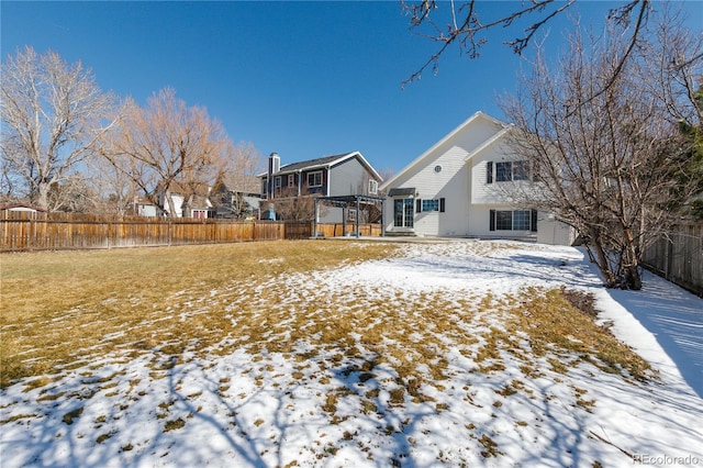 snowy yard featuring a fenced backyard