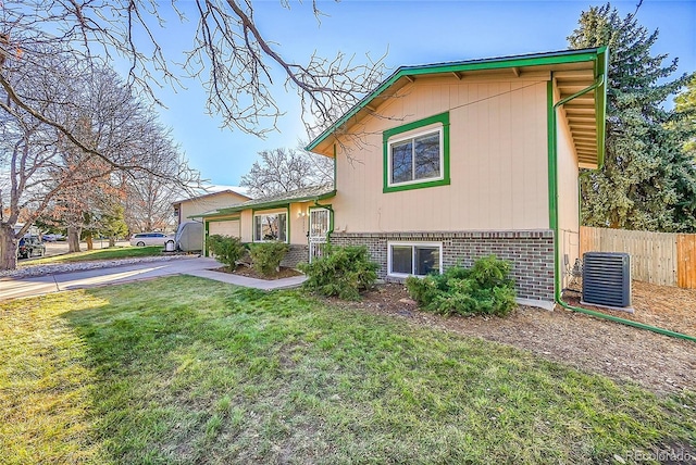 split level home with central AC unit and a front yard