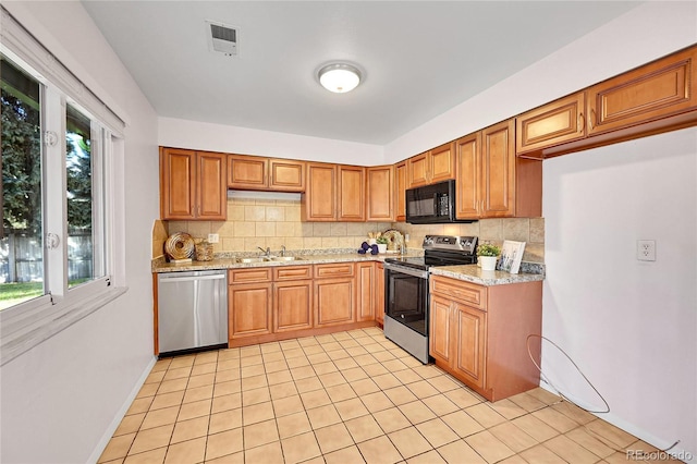 kitchen featuring sink, stainless steel appliances, light stone counters, decorative backsplash, and light tile patterned floors