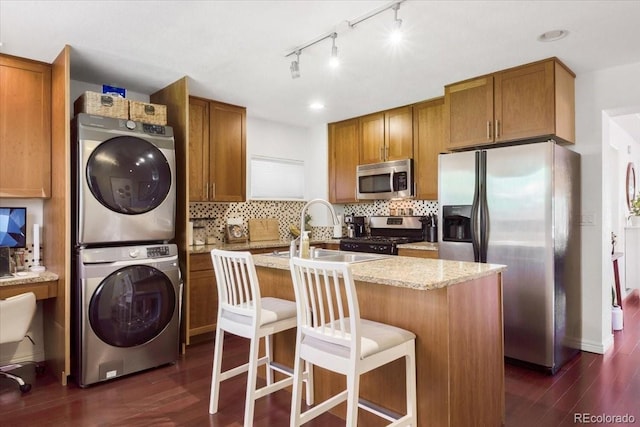 3929 Shoshone St, Denver, CO 80211 - kitchen featuring stacked washing machine and dryer, stainless steel appliances, a sink, dark wood finished floors, and brown cabinets