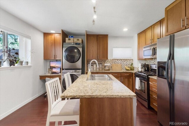 3929 Shoshone St, Denver, CO 80211 - kitchen with stainless steel appliances, estacked washer and dryer, a sink, brown cabinetry, and recessed lighting