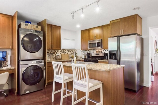3929 Shoshone St, Denver, CO 80211 - kitchen with stacked washer / drying machine, stainless steel appliances, dark wood-style flooring, and brown cabinets