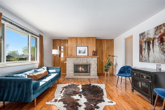 living area with a fireplace, wood walls, and light wood-style floors