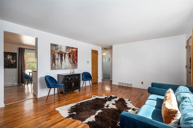 living room featuring visible vents, baseboards, and wood finished floors