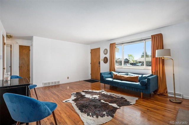 living area featuring baseboards, visible vents, and wood finished floors