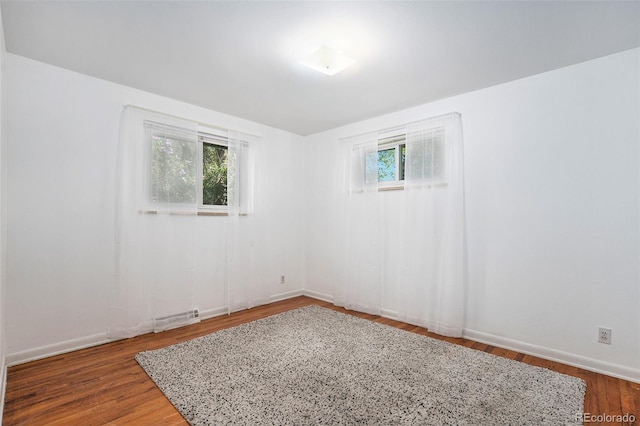 spare room featuring visible vents, baseboards, and wood finished floors