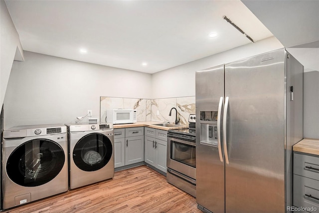 washroom with laundry area, washing machine and clothes dryer, a sink, light wood-style floors, and recessed lighting