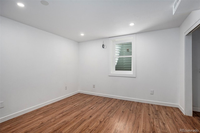 empty room featuring baseboards, recessed lighting, and wood finished floors