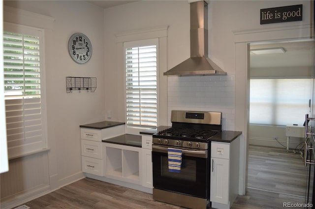 1215 10th Ave, Greeley, CO 80631 - kitchen with stainless steel gas range, wall chimney range hood, wood finished floors, dark countertops, and decorative backsplash
