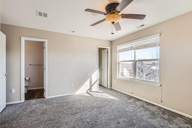 unfurnished bedroom with connected bathroom, ceiling fan, and dark colored carpet