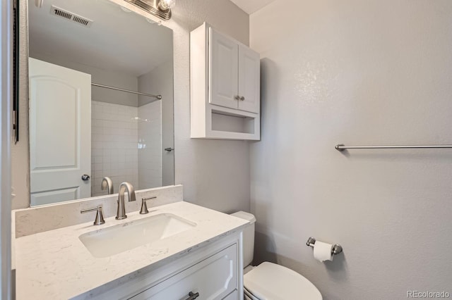 bathroom with vanity, a tile shower, and toilet