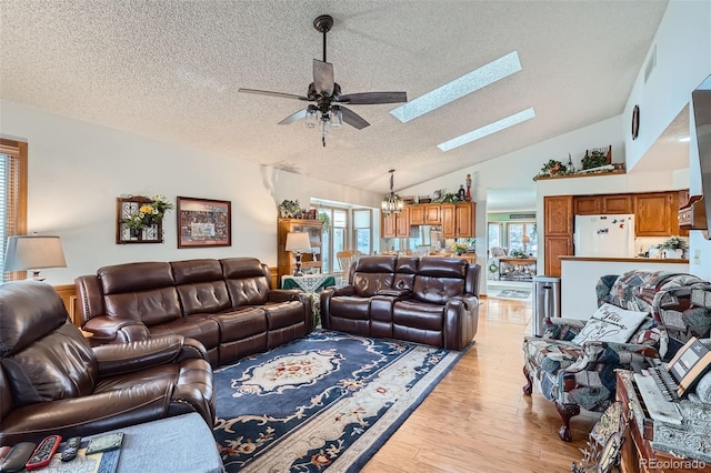 living room with ceiling fan with notable chandelier, light wood-type flooring, plenty of natural light, and high vaulted ceiling