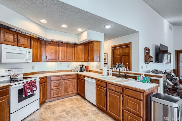 kitchen featuring kitchen peninsula, a textured ceiling, white appliances, and sink