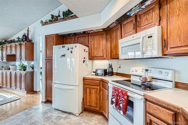 kitchen with a textured ceiling, lofted ceiling, and white appliances