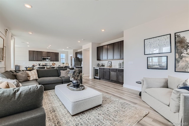 living room featuring light wood finished floors, wine cooler, baseboards, and recessed lighting