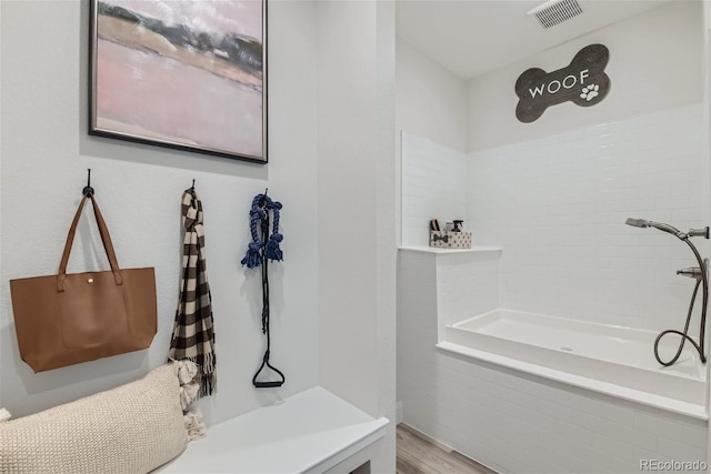 bathroom with visible vents, tiled shower, and wood finished floors