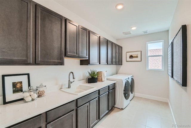 laundry area with washing machine and clothes dryer, cabinet space, visible vents, a sink, and baseboards