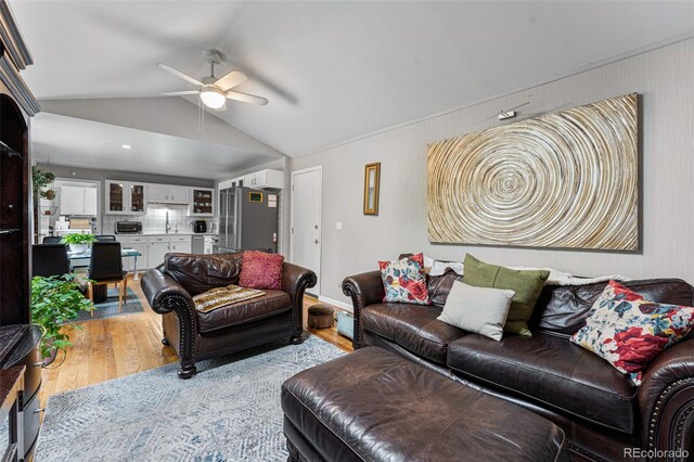 living room with ceiling fan, sink, vaulted ceiling, and light hardwood / wood-style floors