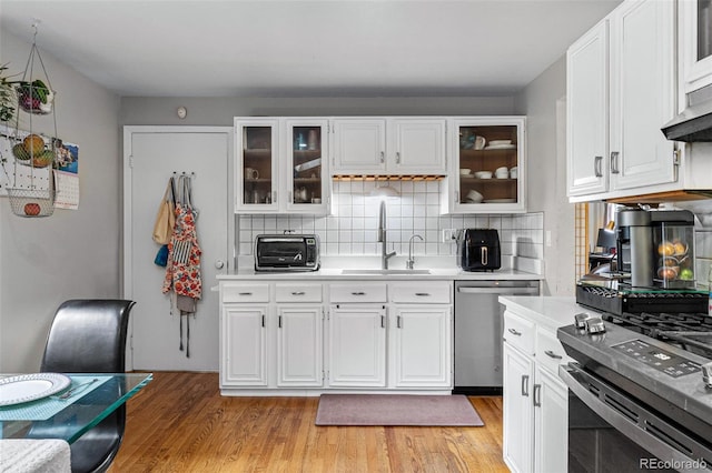 kitchen with tasteful backsplash, light hardwood / wood-style flooring, appliances with stainless steel finishes, and sink