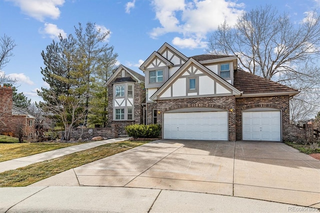 tudor house featuring brick siding, stucco siding, concrete driveway, an attached garage, and a front yard