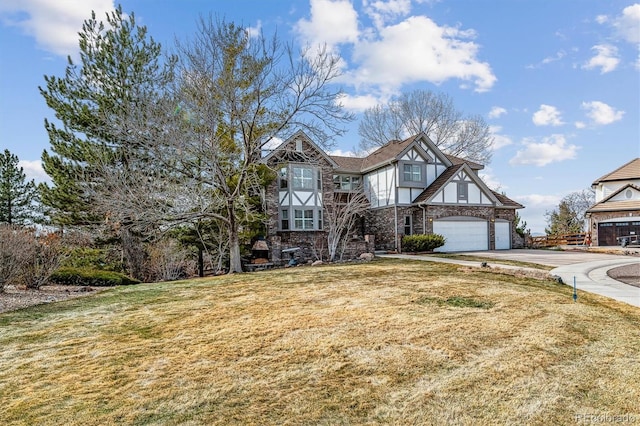 tudor-style house featuring driveway, a front yard, and stucco siding