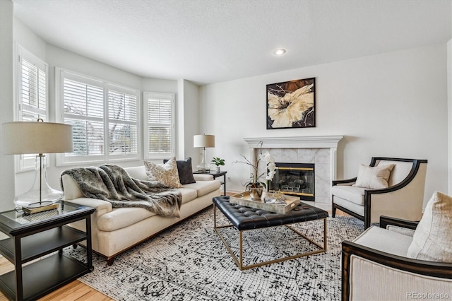 living room with a wealth of natural light, a premium fireplace, wood finished floors, and recessed lighting